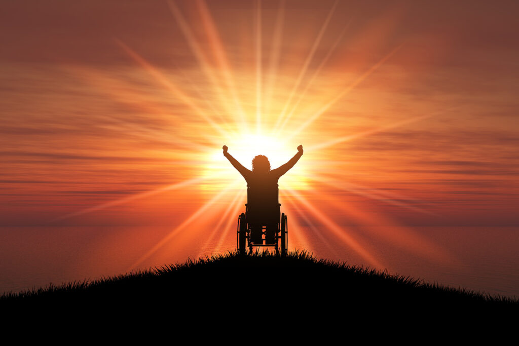 Silhouette of lady in a wheelchair at sunset or sunrise.
